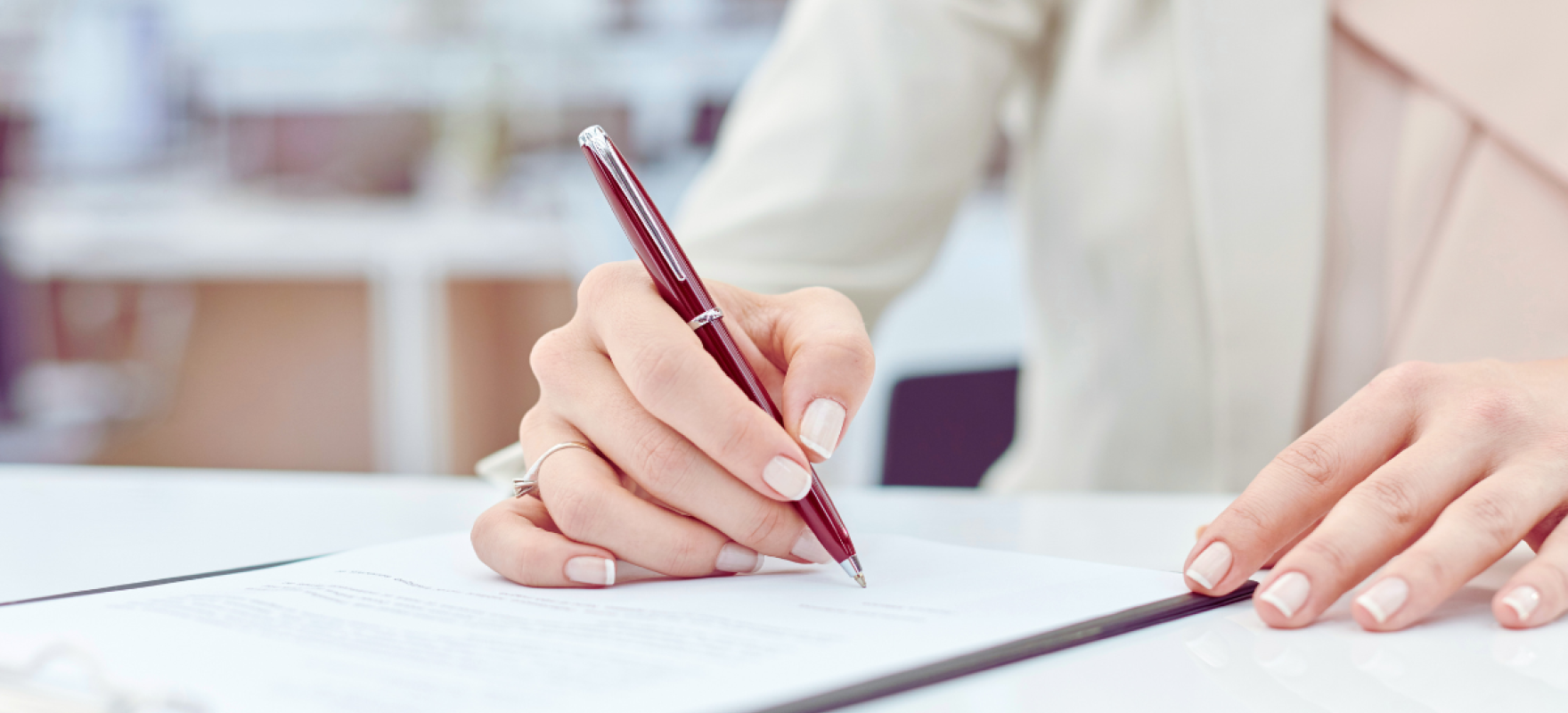 naise käsi dokumendile alla kirjutamas
